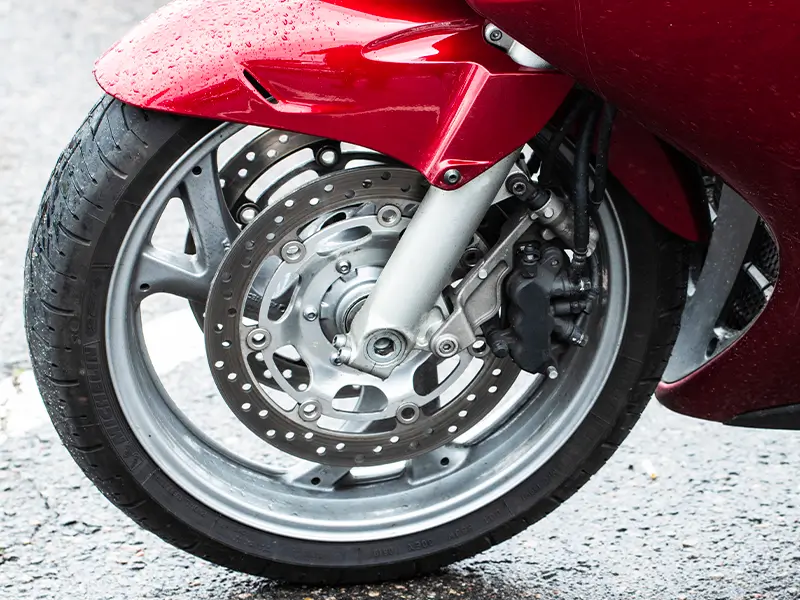 Pneu moto monté sur roue avant avec système de freinage, service pneus moto chez Bomerée-Pneus.